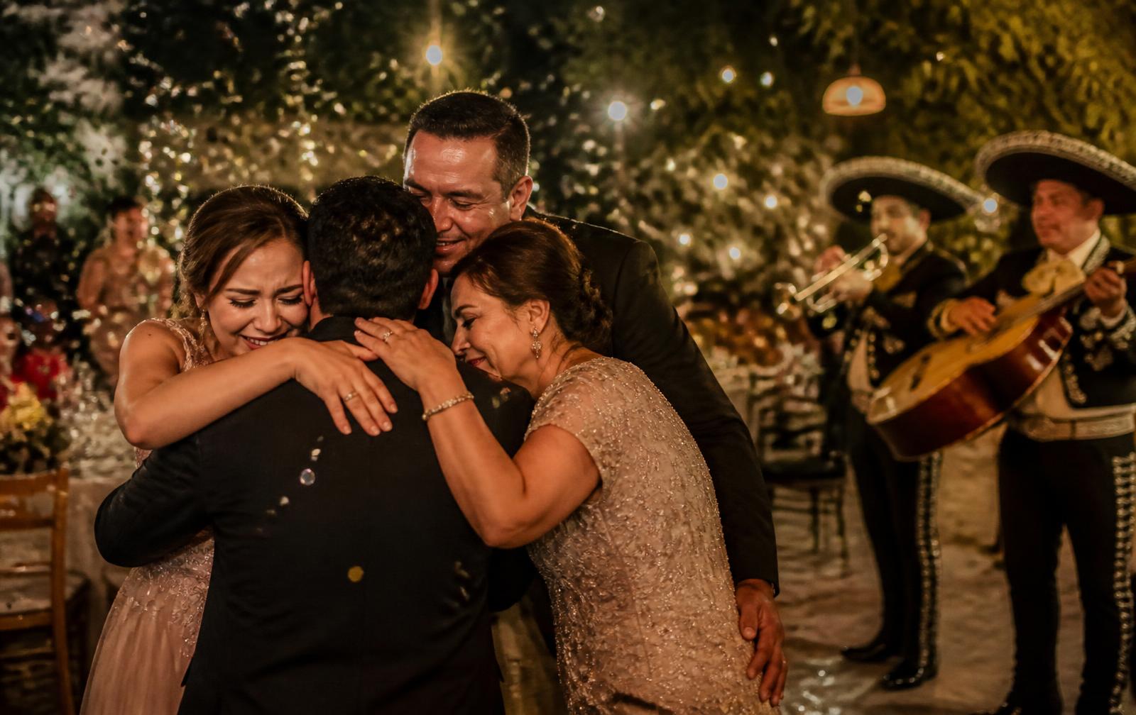 Familia abrazándose y celebrando durante una fiesta amenizada por mariachi.