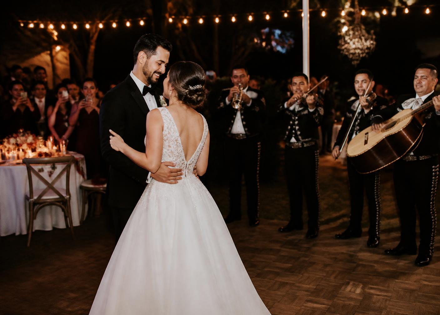 Novios bailando mientras un mariachi toca en una boda al aire libre.