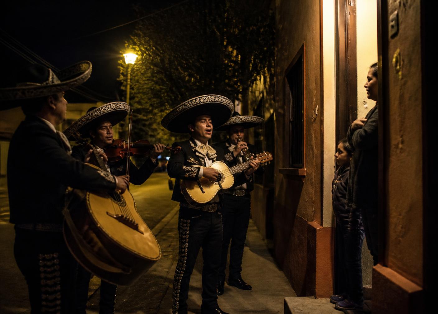 Mariachi dando una serenata nocturna en la puerta de una casa.